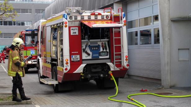 Ein Feuerwehrmann steht neben einem geöffneten Feuerwehrwagen.