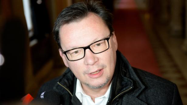 Ein Mann mit Brille spricht in Mikrofone.