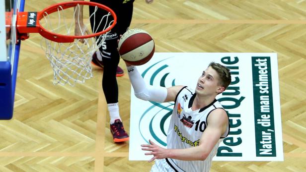Ein Basketballspieler wirft den Ball in den Korb.