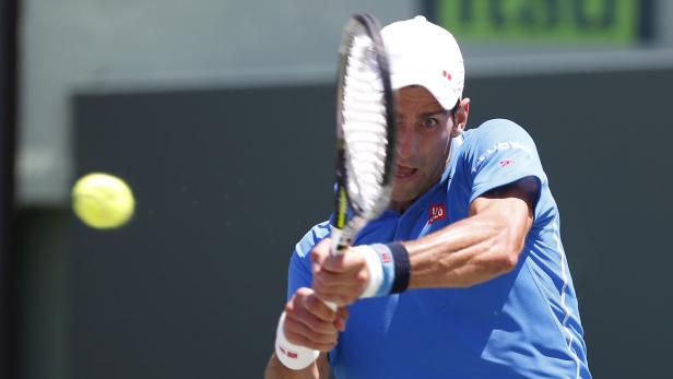 Novak Đoković schlägt einen Tennisball während eines Spiels.