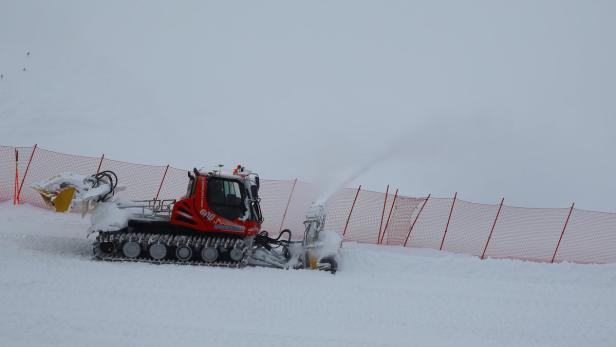 Eine rote Pistenraupe räumt Schnee auf einer Skipiste.