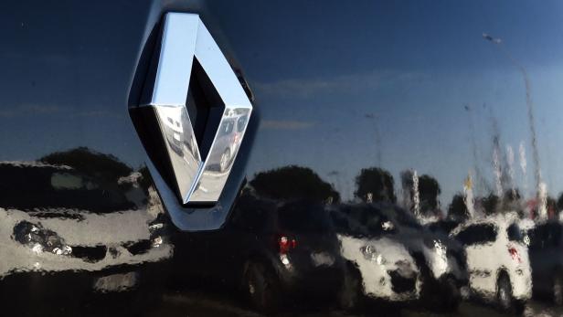 Das Renault-Logo auf der Motorhaube eines Autos spiegelt eine Reihe geparkter Fahrzeuge wider.