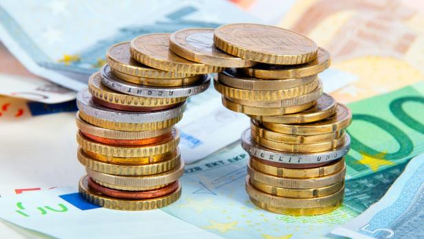 Euro-Münzen sind in zwei Türmen auf Geldscheinen gestapelt.