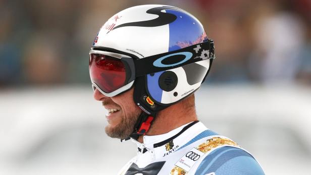 Ein Skirennfahrer mit Helm und Skibrille lächelt.