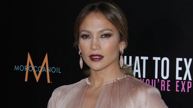 Jennifer Lopez posiert auf einer Veranstaltung vor einer Werbewand.