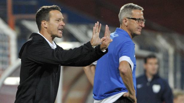 Ein Fußballtrainer gestikuliert während eines Spiels, ein weiterer Mann steht daneben.