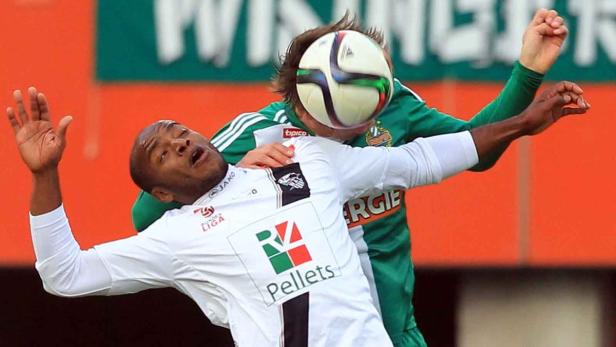 Ein Fußballspieler köpft den Ball, während ein anderer Spieler ihn zu Fall bringt.