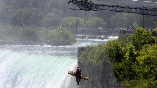 Ein Rettungsteam führt eine Übung an einem Wasserfall mit einem Tragekorb durch.