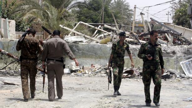 Militärpersonal geht durch eine zerstörte städtische Umgebung.