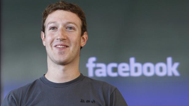 Mark Zuckerberg vor einem Facebook-Logo lächelt.