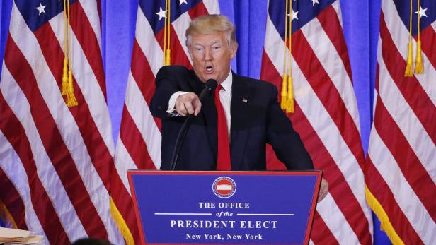 Donald Trump spricht vor amerikanischen Flaggen von einem Rednerpult.