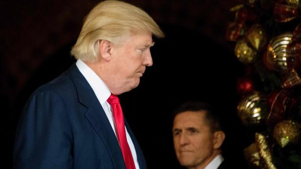 Donald Trump mit roter Krawatte vor einem Weihnachtsbaum.