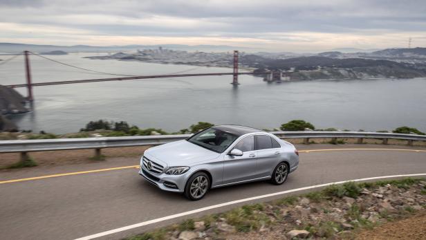 Eine silberne Mercedes-Benz Limousine fährt auf einer kurvenreichen Straße mit Blick auf die Golden Gate Bridge.