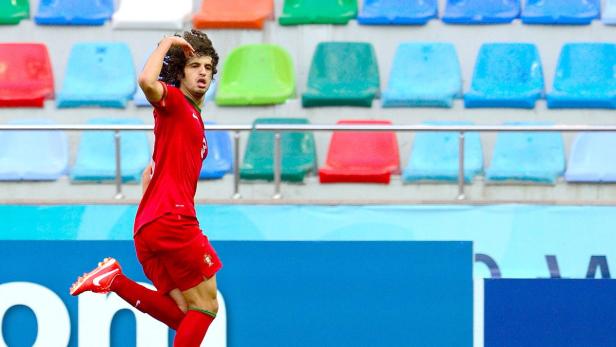 Ein Fußballspieler im roten Trikot jubelt vor einer Tribüne.