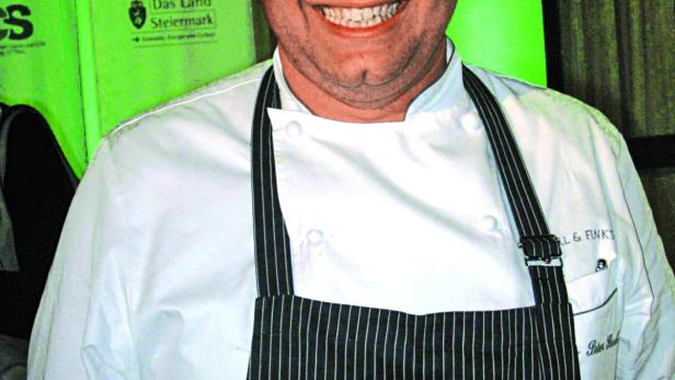 Ein lächelnder Koch in Kochuniform und Schürze.