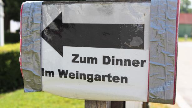 Ein Schild mit einem Pfeil und der Aufschrift „Zum Dinner Im Weingarten“.
