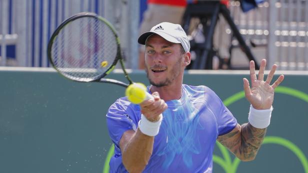 Ein Tennisspieler schlägt einen gelben Tennisball mit seinem Schläger.