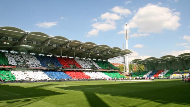 Ein Fußballstadion mit Zuschauern, die grüne, weiße, blaue und rote Farben zeigen.