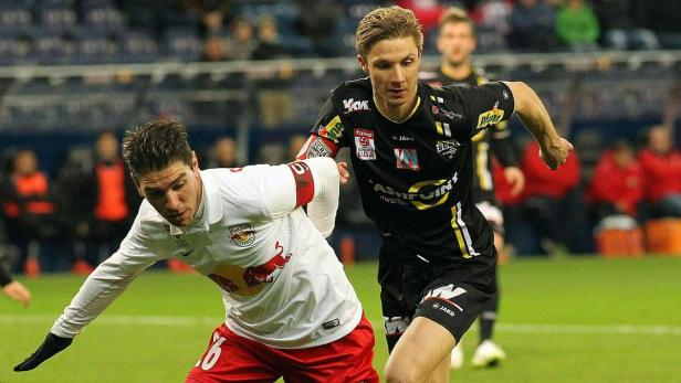 Zwei Fußballspieler kämpfen um den Ball während eines Spiels.