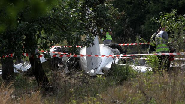 Die Trümmer eines abgestürzten Flugzeugs in einem Feld, abgesperrt mit rot-weißem Band.