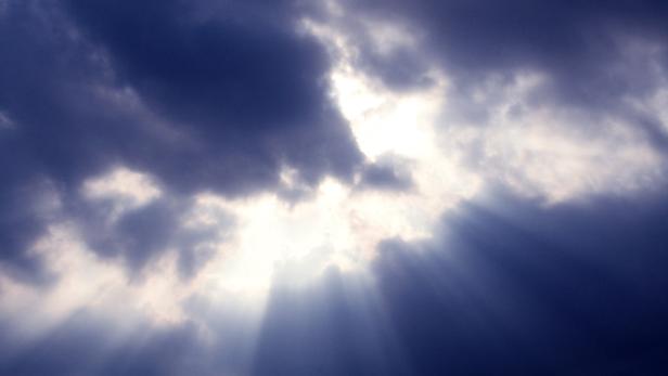 Sonnenstrahlen scheinen durch dunkle Wolken.