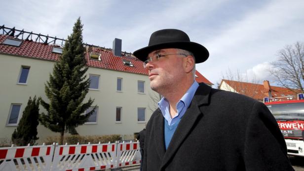 Bedrohter Ex-Bürgermeister vor beschädigtem Asylbewerberheim.