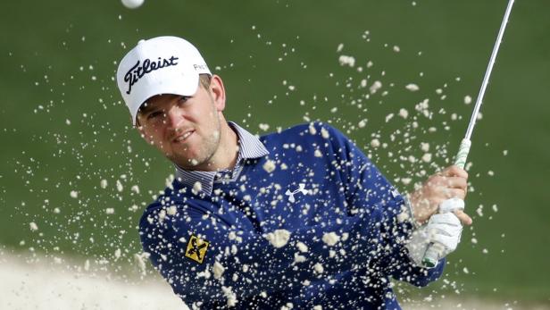 Ein Golfspieler schlägt einen Ball aus einem Sandbunker.