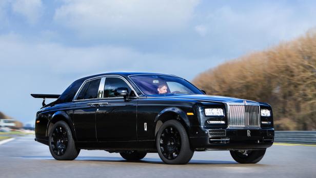 Ein schwarzer Rolls-Royce fährt auf einer Rennstrecke.