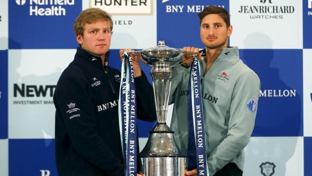 Zwei Männer halten eine Trophäe mit Bändern des Oxford & Cambridge Boat Race.