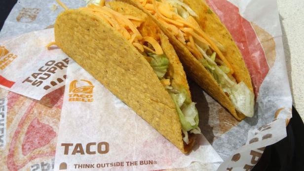 Drei Tacos mit Salat und Käse liegen auf einer Taco-Bell-Verpackung.