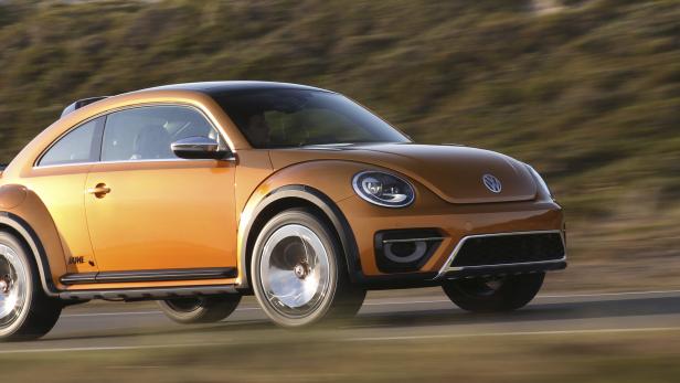 Ein orangefarbener VW Käfer „Dune“ fährt auf einer Straße.