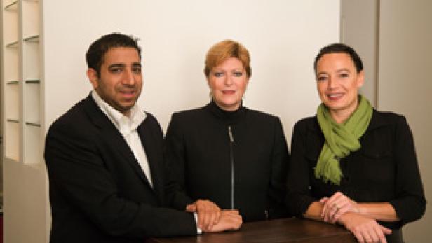 Drei Personen posieren für ein Gruppenfoto vor einer hellen Wand.