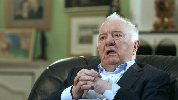 Ein älterer Mann sitzt in einem Sessel und spricht.