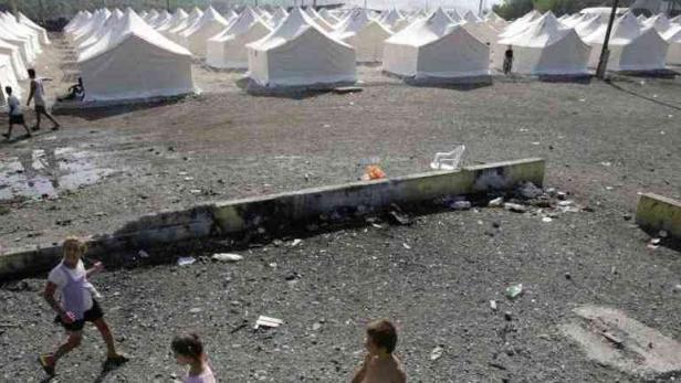 Ein Flüchtlingslager mit vielen weißen Zelten und spielenden Kindern.