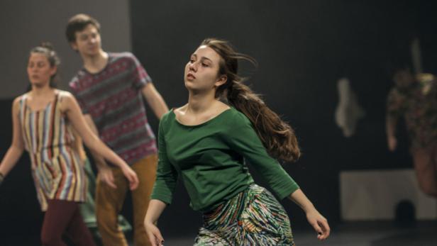Eine junge Frau tanzt mit anderen Tänzern auf einer Bühne.
