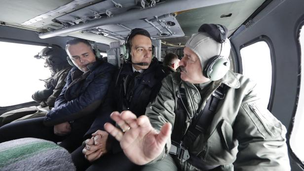 Mehrere Männer sitzen in einem Hubschrauber und tragen Headsets.