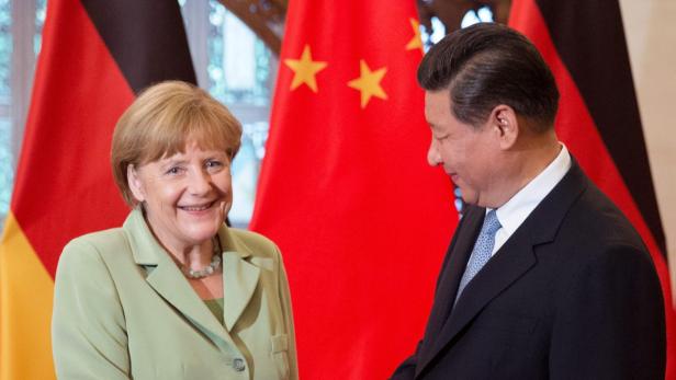 Angela Merkel und Xi Jinping vor deutschen und chinesischen Flaggen.