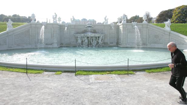 Ein Mann joggt vor dem Schloss Belvedere in Wien an einem Brunnen vorbei.