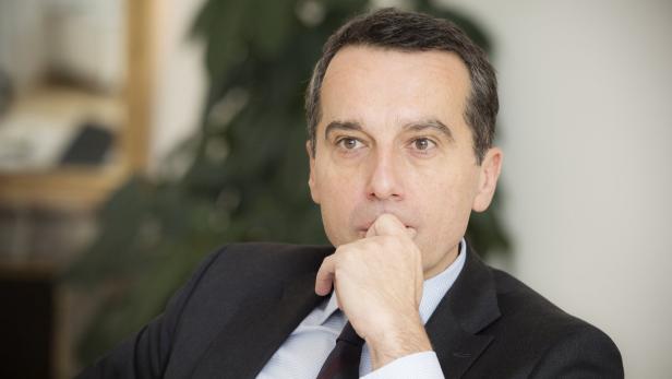 Ein Mann im Anzug sitzt nachdenklich da und berührt sein Kinn.