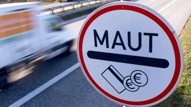 Ein rundes Schild mit der Aufschrift „MAUT“ und Symbolen für Kartenzahlung und Euro-Münzen an einer Autobahn.