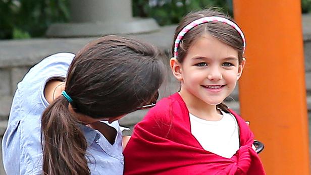 Ein junges Mädchen mit einem roten Tuch lächelt in die Kamera.