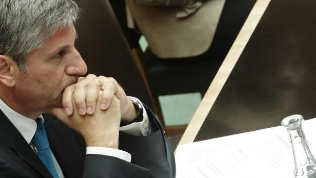 Ein Mann im Anzug sitzt an einem Tisch und denkt nach.