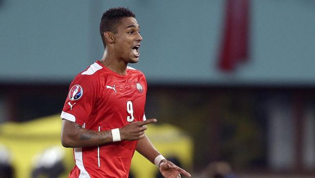 Ein Fußballspieler in rotem Trikot mit der Nummer 9 gestikuliert und ruft etwas.