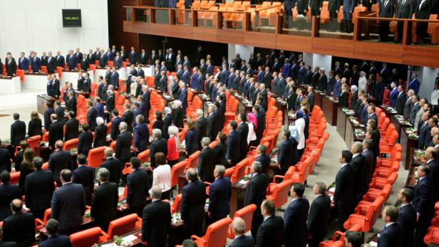 Eine Versammlung von Menschen in einem großen Saal mit orangefarbenen Sitzen.