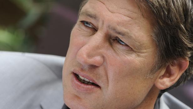 Nahaufnahme eines Mannes mit hellen Augen und grauem Haar, der nach oben blickt.