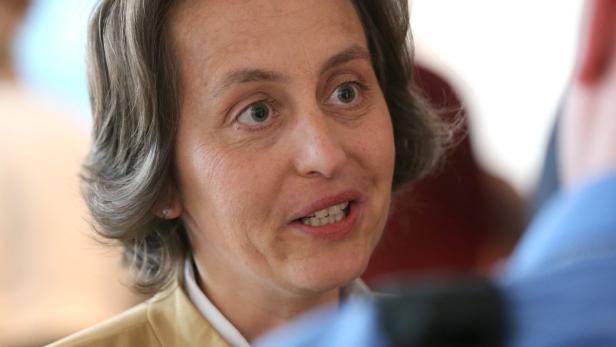 Eine Frau mit braun-grauen Haaren spricht mit jemandem.