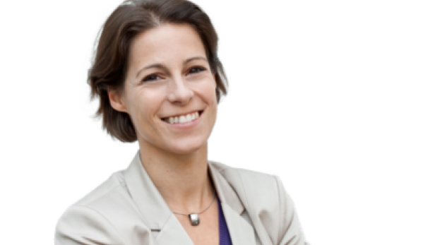 Eine lächelnde Frau mit kurzem braunem Haar trägt ein helles Jackett.