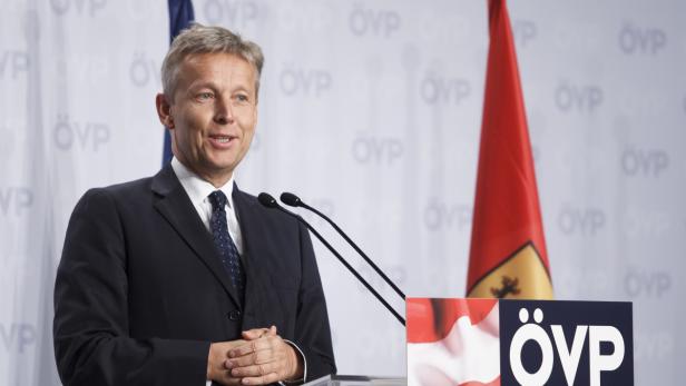 Ein Mann im Anzug spricht vor einem ÖVP-Hintergrund.