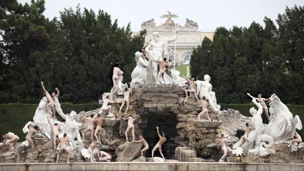 Der Neptunbrunnen im Schlosspark Schönbrunn mit vielen nackten Personen, die auf den Statuen posieren.