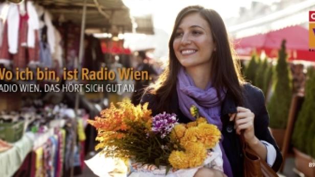 Eine lächelnde Frau mit Blumen auf einem Markt, im Hintergrund ein Radio Wien Logo.